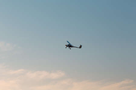 Small single engine airplane flying against sunset sky.