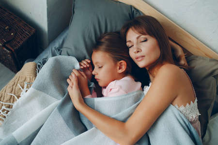 Mother sleep hugging with little daughter girl. Family single parenting mothers day and good night concept.の写真素材