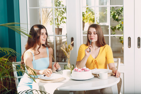 Women happy friends at home sitting and smiling with white birthday cake.の写真素材