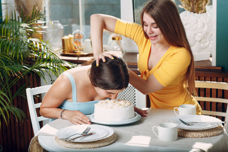 Young woman dips face in white cake with cream. Happy birthday conceptの写真素材