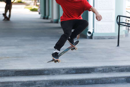 Young boy riding trick on skateboard in city.の写真素材