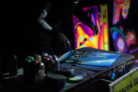 Young street artist finishing his artwork with spray color paint and fire in dark night.の写真素材