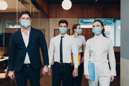 Businessman and businesswoman team in face masks walking to office meeting. Business people group conference discussion conceptの写真素材