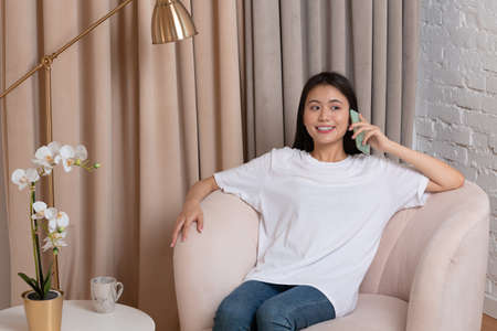Portrait of asian woman enjoying using speaking with friend mobile phone at apartment interior...