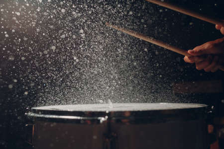 Close up drum sticks drumming hit beat rhythm on drum surface with splash water drops backlightの写真素材