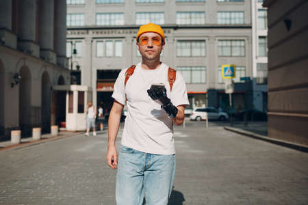 Young disabled man tourist using mobile phone with artificial prosthetic hand and walking at sunny city street outdoorの写真素材