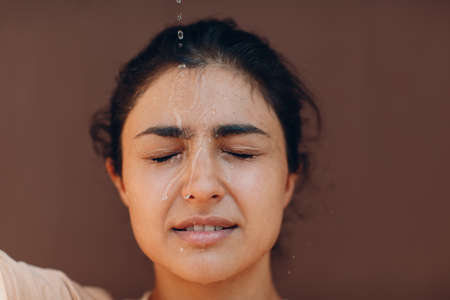 Stressed woman suffering of heatstroke and refreshing pouring with cold water outside. Weather abnormal very heat conceptの写真素材