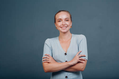 Portrait of young smiling european woman. Beautiful happy blonde girl wears t-shirt and looks at camera. Studio shoot isolated on blue background.の写真素材
