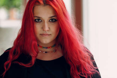 European plus size woman portrait outdoor street city. Young red pink haired body positive girl.