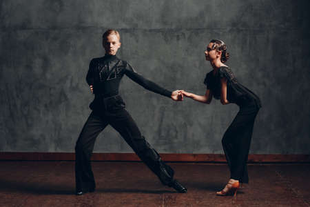 Couple young man and woman in black dress dancing in ballroom dance rumbaの写真素材