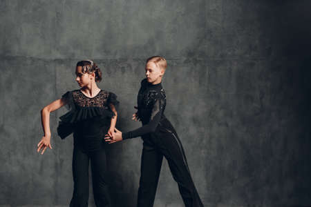 Young couple in black dress dancing in ballroom. Two european professional sport dancers dances modern contemporary pair dance. Man and woman in passion.の写真素材