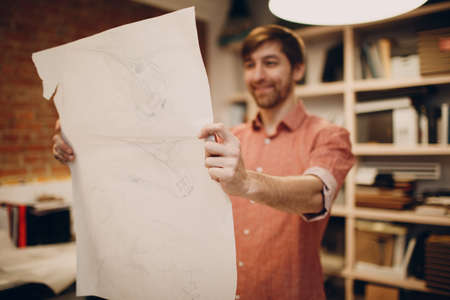 Architect hold in hands blueprint layout design project at office european bureauの写真素材