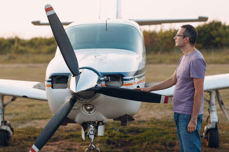 Pilot man standing next to a small private airplane