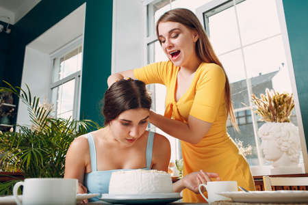 Young woman dips face in white cake with cream. Happy birthday conceptの写真素材