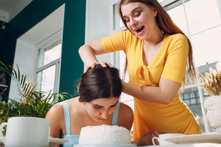 Young woman dips face in white cake with cream. Happy birthday conceptの写真素材