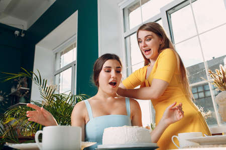 Young woman dips face in white cake with cream. Happy birthday conceptの写真素材