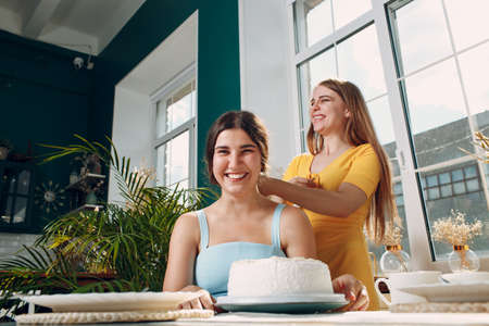 Young woman dips face in white cake with cream. Happy birthday conceptの写真素材