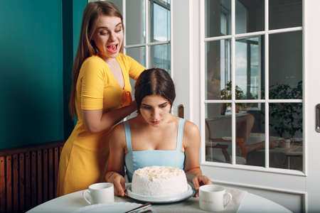 Young woman dips face in white cake with cream. Happy birthday conceptの写真素材