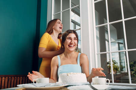 Young woman dips face in white cake with cream. Happy birthday conceptの写真素材