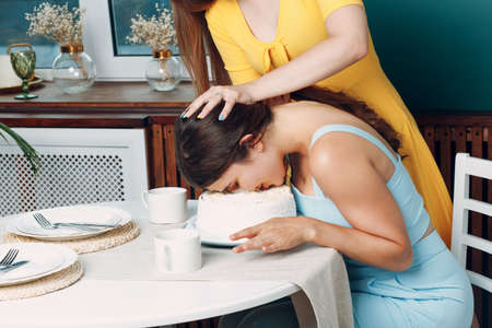 Young woman dips face in white cake with cream. Happy birthday conceptの写真素材