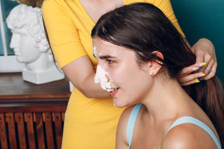Young woman dips face in white cake with cream. Happy birthday conceptの写真素材