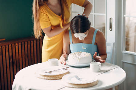 Young woman dips face in white cake with cream. Happy birthday conceptの写真素材