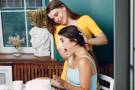 Young woman dips face in white cake with cream. Happy birthday conceptの写真素材