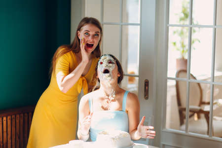 Young woman dips face in white cake with cream. Happy birthday conceptの写真素材