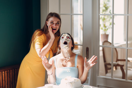 Young woman dips face in white cake with cream. Happy fun birthday conceptの写真素材