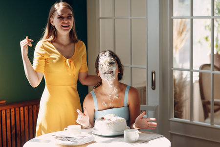 Young woman dips face in white cake with cream. Happy birthday conceptの写真素材