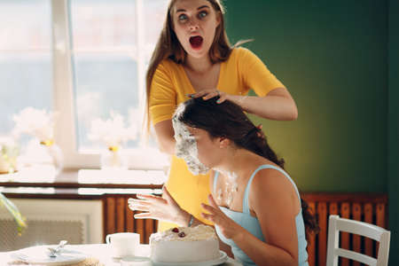 Young woman dips face in white cake with cream. Happy birthday conceptの写真素材
