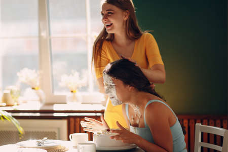 Young woman dips face in white cake with cream. Happy birthday conceptの写真素材