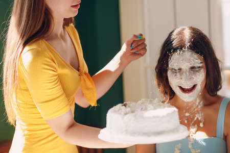 Young woman dips face in white cake with cream. Happy birthday conceptの写真素材