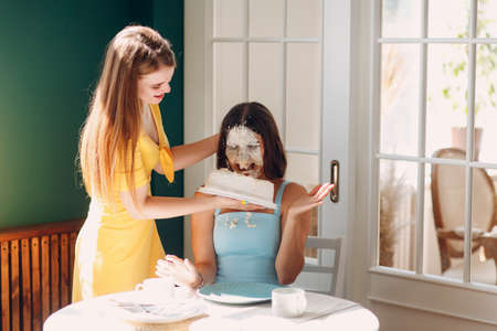 Young woman dips face in white cake with cream. Happy birthday conceptの写真素材