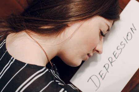 Woman portrait with white sheet paper labeled word Depression. Hidden depression concept.