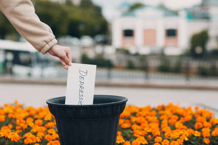 Woman throws sheet with word depression into trash can. Psychology help.の写真素材