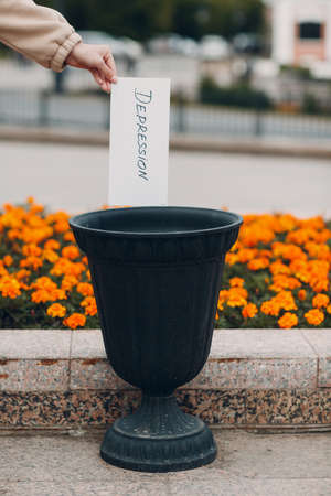 Woman throws sheet with word depression into trash can. Psychology help.の写真素材