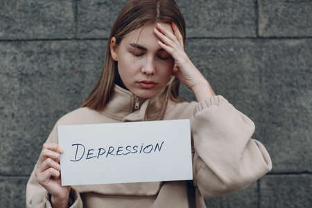 Girl holds in hand sheet of paper with word Depression.の写真素材