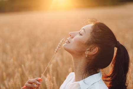 Portrait of a beautiful brunette woman with ears of wheat on her face.の写真素材