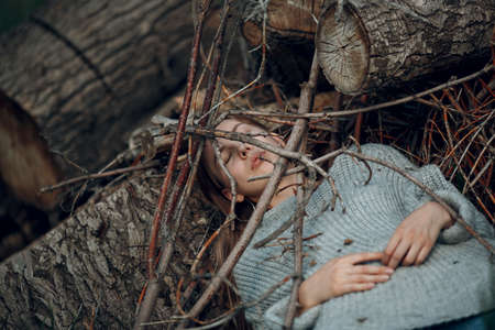 Teenager young woman lying outdoor in the park under dry tree branches. Sex maniac crime rape violence conceptの写真素材