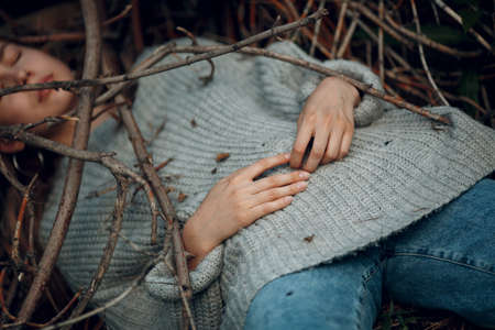 Teenager young woman lying outdoor in the park under dry tree branches. Sex maniac crime rape violence conceptの写真素材