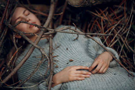Teenager young woman lying outdoor in the park under dry tree branches. Sex maniac crime rape violence conceptの写真素材