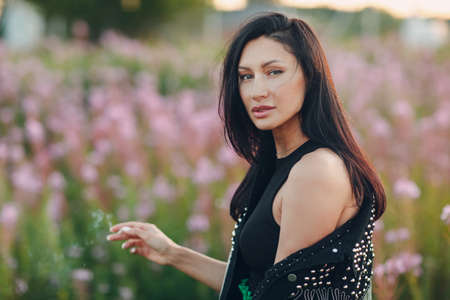 Young brunette woman on blooming Sally flower field. Lilac flowers and girlの写真素材
