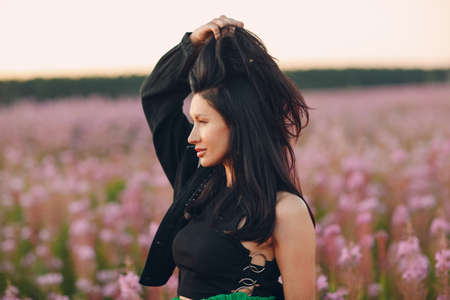 Young brunette woman on blooming Sally flower field. Lilac flowers and girlの写真素材
