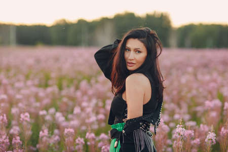 Young brunette woman on blooming Sally flower field. Lilac flowers and girlの写真素材