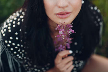 Young brunette woman on blooming Sally flower field. Lilac flowers and girlの写真素材