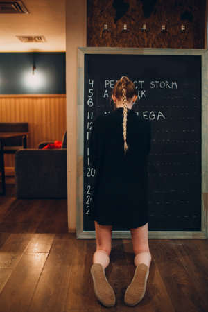 Young woman writing cafe menu on black desk chalkboard using chalkの写真素材