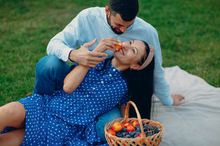 Young adult woman and man couple picnic at green grass meadow in parkの写真素材