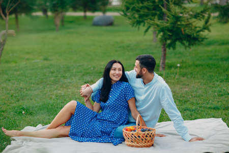 Young adult woman and man couple picnic at green grass meadow in parkの写真素材