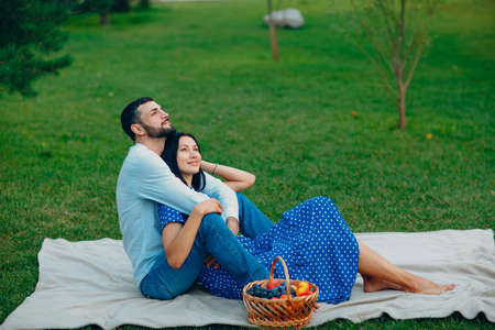 Young adult woman and man couple picnic at green grass meadow in parkの写真素材